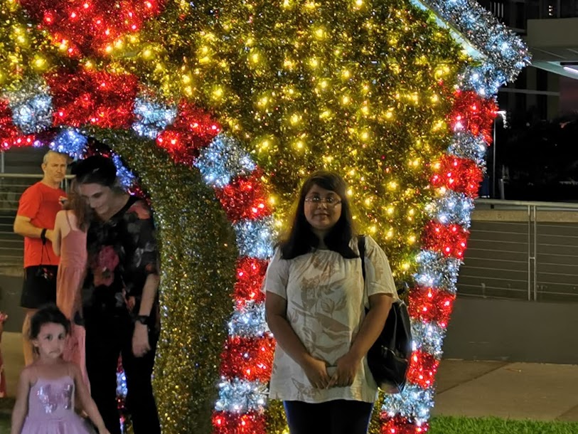 Sarah standing beneath colourful holiday lights