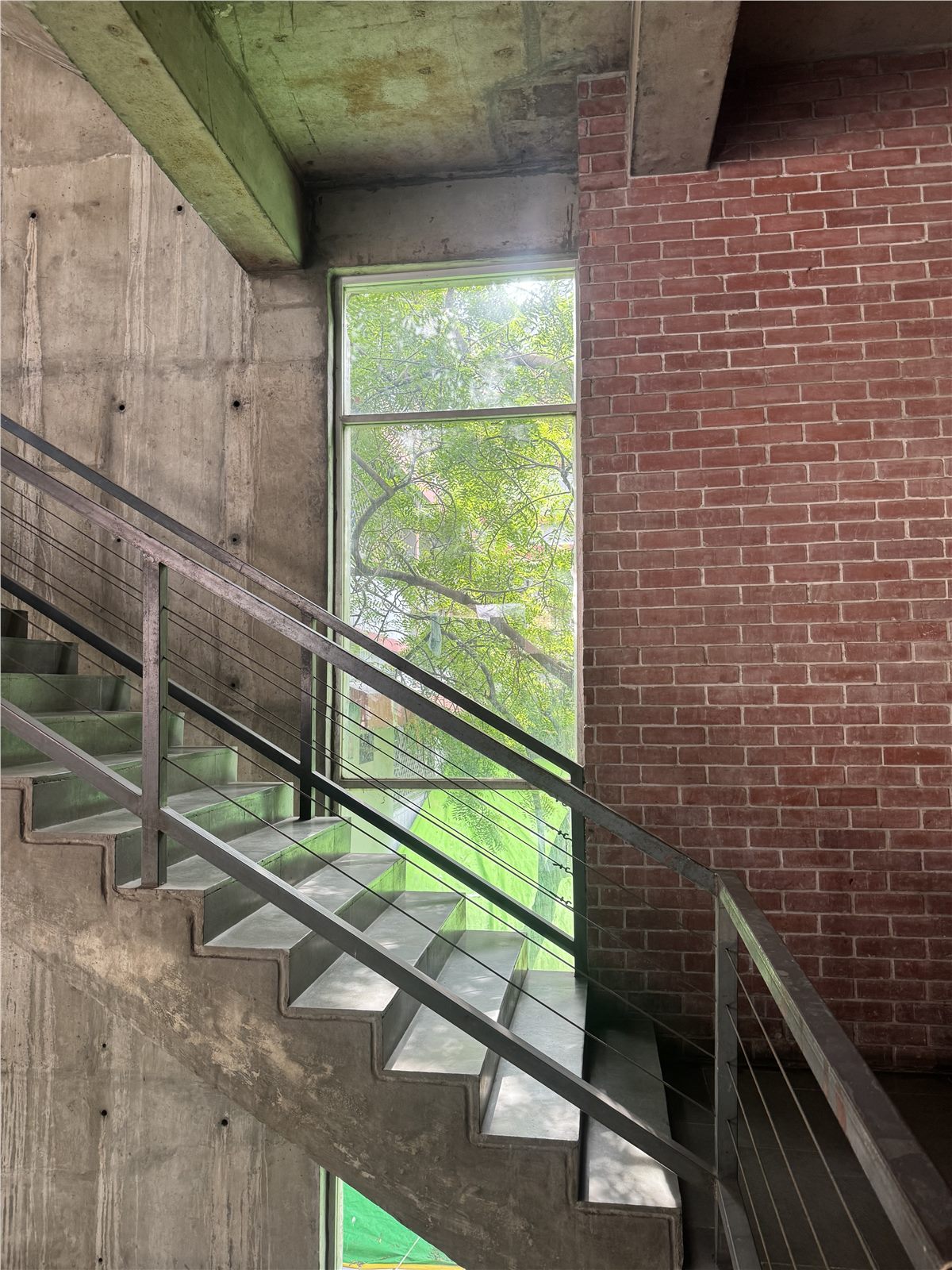 Concrete stairway beside a sunlit window and brick wall
